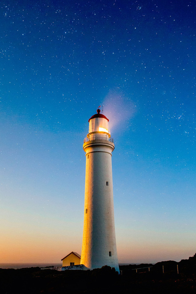 Tall, narrow lighthouse at sunset.