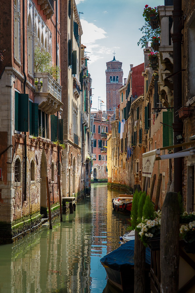 A Venice canal with balcony flowers and green shutters