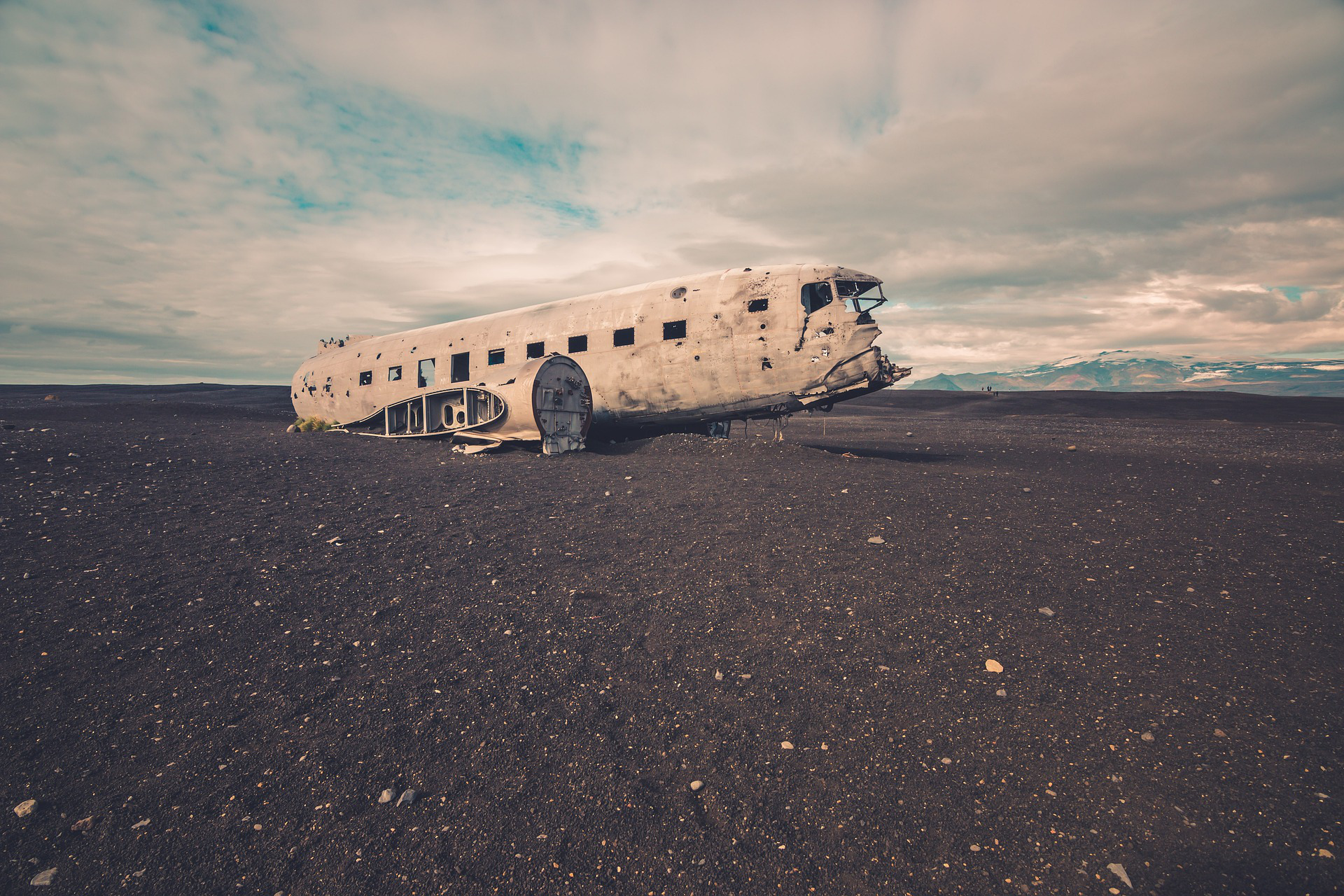 The wreckage of an abandoned plane on a landscape of volcanic sand